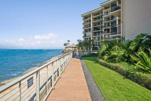 a walkway next to a building next to the ocean at Hololani A204 in Kahana