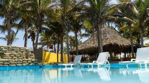 uma piscina com espreguiçadeiras e palmeiras em Bali Lodge Máncora - Playa, Piscina & Desayuno em Máncora