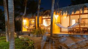 um resort com redes e palmeiras à noite em Bali Lodge Máncora - Playa, Piscina & Desayuno em Máncora