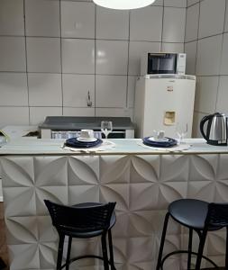 eine Küche mit zwei Stühlen und einer Theke mit zwei Gläsern in der Unterkunft Loft Aconchegante/Climatizado in Miguel Pereira