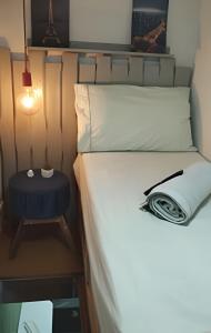 a bed in a small room with a side table at Micro Flat Compacto c/Banheiro in Volta Redonda