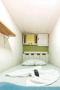 a small room with a bed with a remote control on it at Micro Flat Compacto c/Banheiro in Volta Redonda