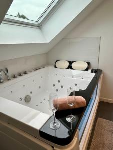 a bathtub with two glasses and two wine glasses at l'Alchimiste - Appartement moderne avec jacuzzi in Bitche