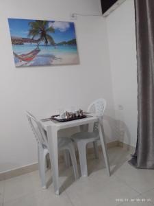 a white table and chairs with a picture on the wall at Recanto Mosaico in São Sebastião