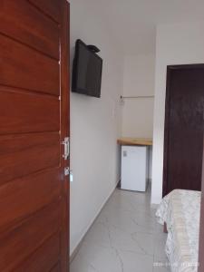 a bedroom with a door and a tv on the wall at Recanto Mosaico in São Sebastião