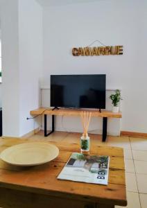 a living room with a table with a television at Appartement avec jardinet dans mas équestre in Saint-Laurent-dʼAigouze