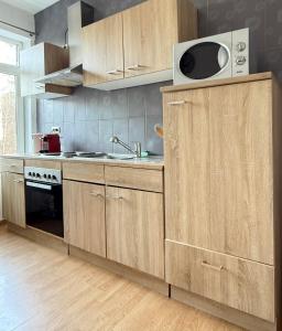 uma cozinha com armários de madeira, uma pia e um micro-ondas em Duplexe Cosy - HERSTAL em Herstal