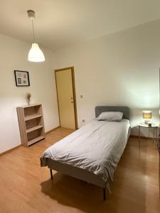um quarto com uma cama, uma mesa e um candeeiro em Duplexe Cosy - HERSTAL em Herstal mais 2 fotografias