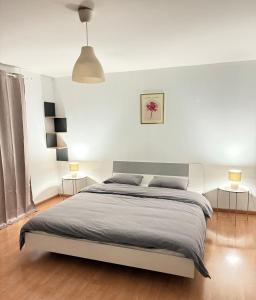 um quarto branco com uma cama e 2 candeeiros em Duplexe Cosy - HERSTAL em Herstal