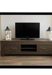 TV de pantalla plana en la parte superior de un centro de entretenimiento de madera en Halte71, en Zandvoort