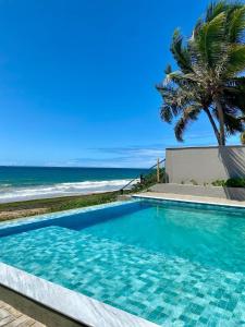 una piscina con una palma e l'oceano di Flat mar a Coruripe