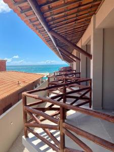 una fila di sedie di legno su un balcone con vista sull'oceano di Flat mar a Coruripe Altre 7 foto