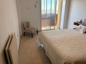 a bedroom with a bed and a chair and a window at Departamento Liban in San Juan