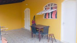 a table and chairs in a room with a yellow wall at Chalés Boraceia Duda in Boracéia