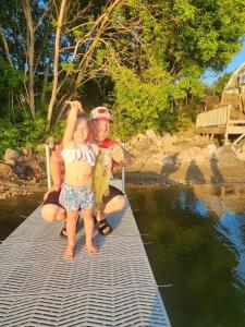 een man en een kind op een steiger met een vis bij Family Shoreline Hideaway in Ortonville
