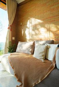 a bed with white pillows and a brick wall at Cabana nas montanhas em Campos do Jordão in Campos do Jordão
