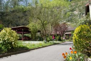 a road in a garden with flowers and a building at Logis Hôtel La Cascade - Lyon Nord in Saint-Genis-les-Ollières