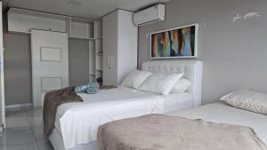two beds in a room with white walls at Apartamento Duplex na Praia Grande 108 VISTA MAR in Arraial do Cabo