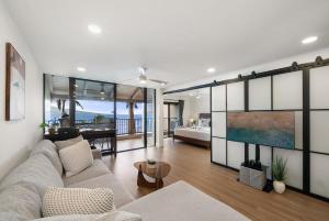 a living room with a couch and a tv and a bedroom at Lauloa 403 · LOA 403 Fully Remodeled Direct Oceanfront 2BD in Wailuku