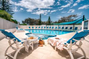 a swimming pool with two chairs and a table at Talisman Beachside in Gold Coast