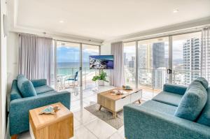 a living room with two blue couches and a table at Talisman Beachside in Gold Coast