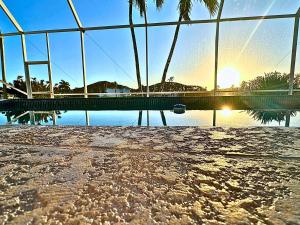 Stunning Intercoastal Waterfront Private Pool Foosball Table Tennis by Vacation Your Way في جزيرة ماركو: منظر لبركة ماء مع غروب الشمس