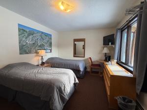 a hotel room with two beds and a desk and a window at Mountain Sports Inn in Killington