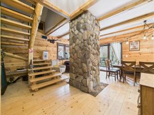 Łosia Chata في Grzybowce: غرفة معيشة كبيرة مع عمود حجري وغرفة طعام