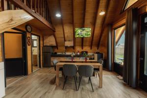 una cucina e una sala da pranzo con tavolo e sedie di Cabana AFrame EmAli a Poiana Teiului