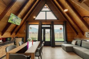 un soggiorno con tavolo e sedie e una grande finestra di Cabana AFrame EmAli a Poiana Teiului