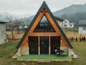 una casa con un tetto triangolare con un tavolo e una sedia di Cabana AFrame EmAli a Poiana Teiului