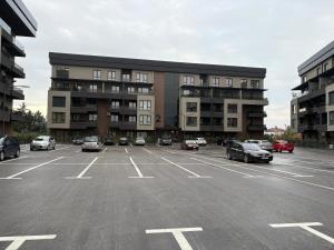 Un estacionamiento con autos estacionados frente a un edificio. en Harmony Airport Apartment, en Skopje