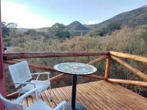a table and chairs on a deck with mountains in the background at La Chakana in Capilla del Monte