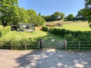 a fence with a gate in a field at The Shepherd's Hut at Hidden Wood Glamping in Corsley