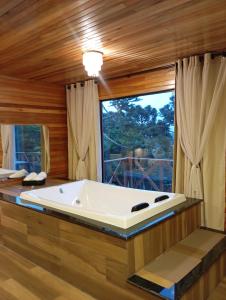 a large bath tub in a room with a window at Cabana Alpen Ville 01 - Rural com Banheira de Hidromassagem in Bom Jardim da Serra