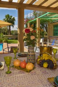 a table with a vase of flowers and fruit on it at Bluegreen Guest House Marrakech in Aït Amara