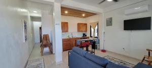 a living room with a blue couch and a kitchen at Lickety Split Unit 3, Northside Ocean View in Caye Caulker