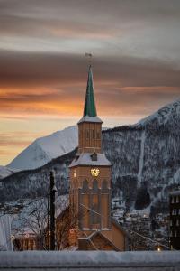 un edificio con una torre dell'orologio con un campanile verde di The Gallery Penthouse by Paramount a Tromsø