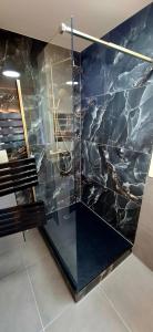 bagno con doccia in vetro e parete in marmo nero di Le Square Inn a Turckheim