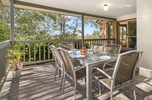 a table and chairs on a deck with a balcony at Blenheim Hideaway by Experience Jervis Bay in Vincentia