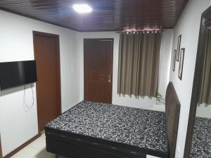 Un dormitorio con una cama y un televisor. en Kitnet Praia do Porto, en Imbituba