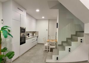 a kitchen with white cabinets and a table and a staircase at playa honda airport suite in Playa Honda