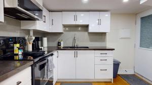 a kitchen with white cabinets and a sink at Stylish Basement Suite for 4 Near Cafes & Parks - Bloor Hotel in Toronto +11 photos