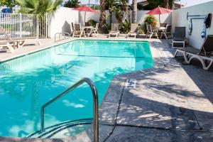 einen Pool mit Stühlen und Sonnenschirmen in einem Hotel in der Unterkunft Motel 6-Bakersfield, CA - East in Bakersfield