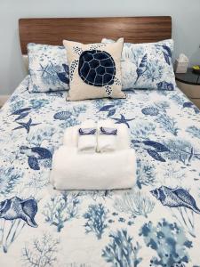 a bed with a blue and white comforter with towels at Close to hard rock stadium and guitar casino in Pembroke Pines