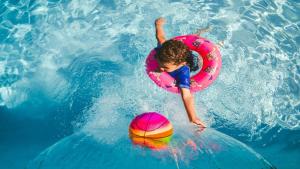 a young child riding a wave in a pool with a ball at Candlewood Suites London South by IHG in London
