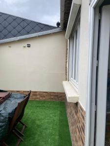 eine kleine Terrasse mit einem Tisch und einem Fenster in der Unterkunft la maison des copains, garage et wifi in Amiens