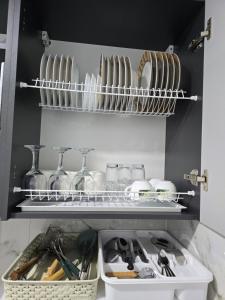 a kitchen shelf with plates and bowls and utensils at Studio modern 10 min de centru, perfect pentru doi in Chişinău