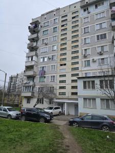 a tall building with cars parked in a parking lot at Studio modern 10 min de centru, perfect pentru doi in Chişinău