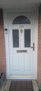 a white front door of a brick house at The Greenwood Guest Room in Brimsdown Station +3 photos